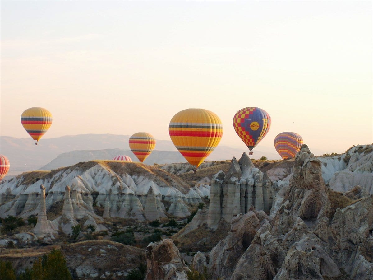 Hot air balloons rising over the fairy chimneys of Cappadocia at sunrise