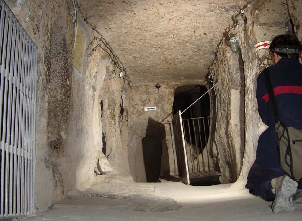 A narrow carved corridor descending between levels of an underground city
